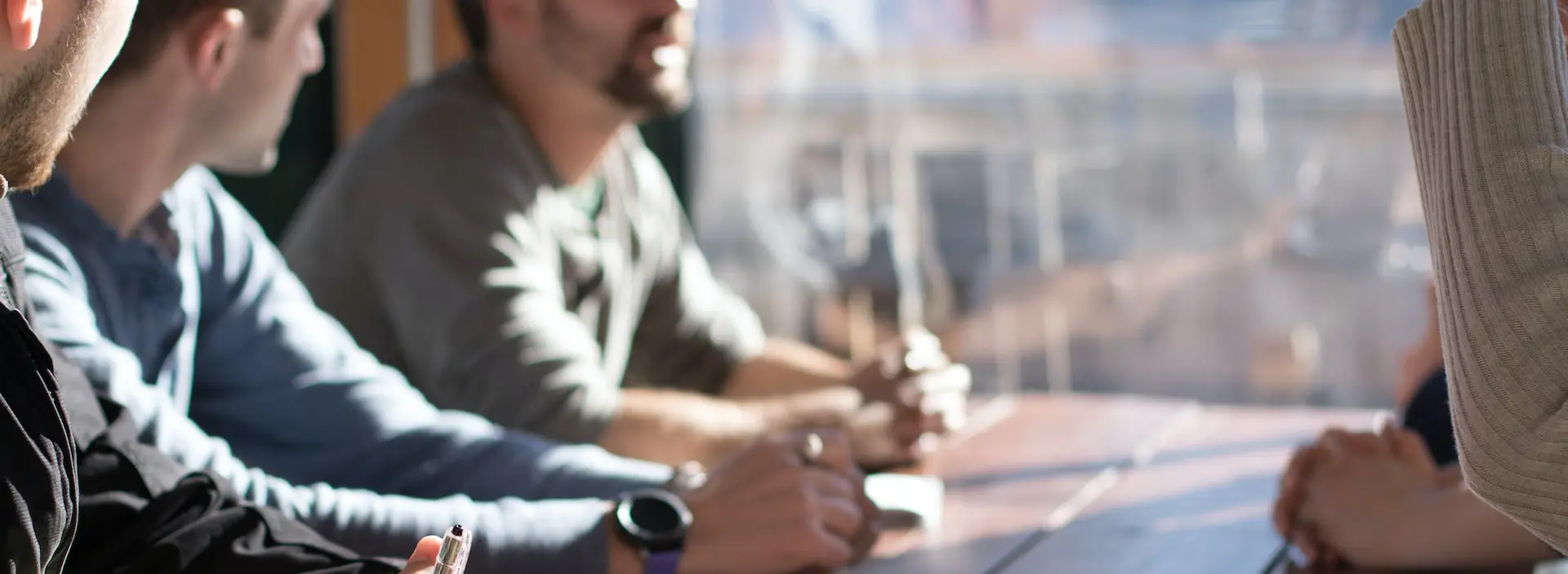 people sitting on chair in front of table while holding pens during daytime